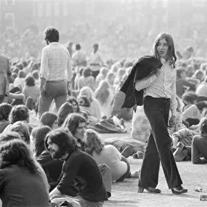A long haired music fan, jack over his shoulder, wanders through the huge crowd