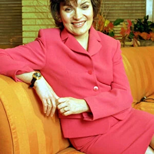 Lorraine Kelly GMTV presenter wearing a pink suit poses on a sofa couch
