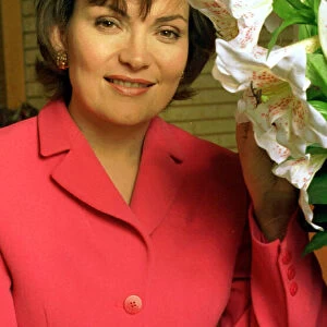 Lorraine Kelly TV presenter wearing a pink suit poses with some flowers