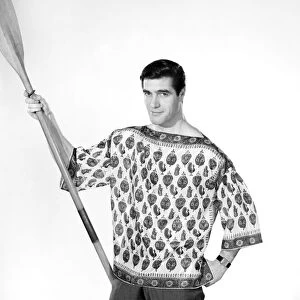 Male model Peter Christian wearing silk shirt seen here holding a oar. Circa 1964