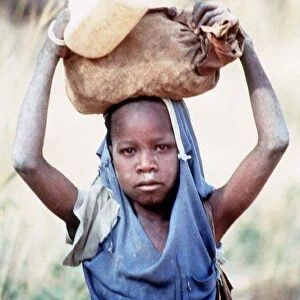 Mali Dogon Tribe a young girl carrying heavy item on her head