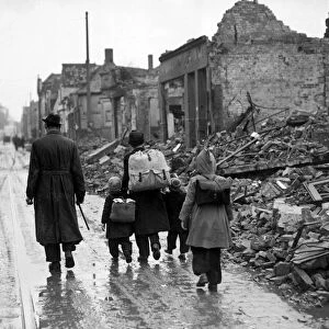 A man with his children walking the streets through a ruined French town during