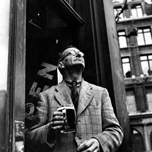 A man holding a tankard of beer in a pub doorway in Holborn. 1946 P009217