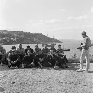 A man takes a photo of a group of men at Brixham Harbour, Devon. 12th April 1957 A man takes a photo of a group of men at Brixham Harbour, Devon. 12th April 1957
