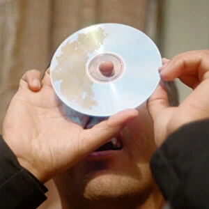 A man watching the solar eclipse through a hole in a CD in Chester. 11th August 1999