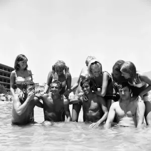 Il calciatore del Manchester United George Best si rinfresca con gli amici, tra cui Mike Summerbee.