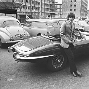 Manchester United footballer George Best with his Jaguar E-Type outside his boutique in