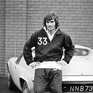 Manchester United star George Best poses next to his Lotus Europa car after a training