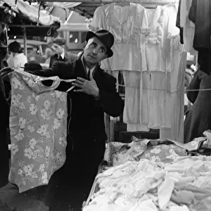 A market trader modelling ladies underwear to gain a sales in Kingston Market circa 1936