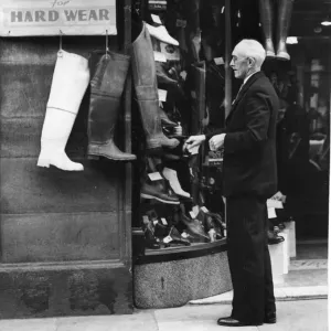 May 1950. Alderman TR Broadbent looking at a shop display of boots outside a shop by May 1950. Alderman TR Broadbent looking at a shop display of boots outside a shop by