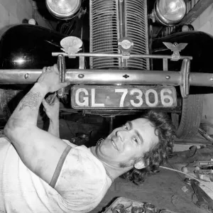 Mechanic underneath a car, making repairs April 1975 75-02158-010