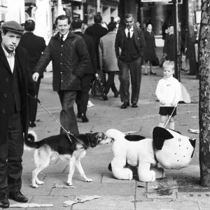 A mechanical toy dog sniffing a tree is being sniffed ata by a real dog on the street A mechanical toy dog sniffing a tree is being sniffed ata by a real dog on the street
