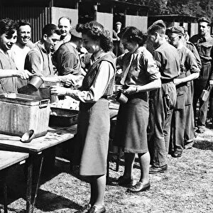 Members of the ATS line up with soldiers to get their first meal in France during WW2