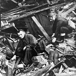 Two members of the emergency services sift through the rubble after another air raid
