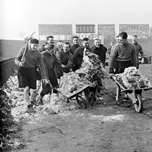Members of the Fulham football team clearing the snow from their pitch before their FA