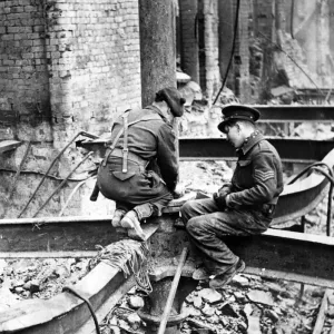 Members of H. M Forces perched on a girder as they place a charge of gelignite in position Members of H. M Forces perched on a girder as they place a charge of gelignite in position