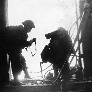 Two members of the home guard, silhouetted, in the doorway of a blitzed building
