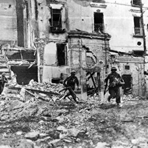 Men of American Infantry regiment moving across an open square in Itri while the town is