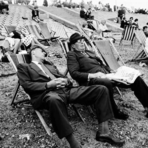 Two men asleep in deckchairs on the beach. August 1964