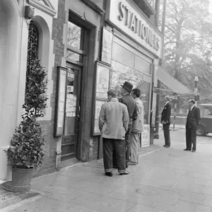 Les hommes regardant les annonces locales et personnelles sur le tableau d'affichage à l'extérieur de la boutique.