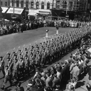 Men of the Manchester Regiment with bayonets fixed march into Cross Street on their way