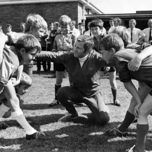 Une mini-réunion de scrum sur le point de se former alors que l'organisateur des entraîneurs du WRU, Ray Williams, discute avec les élèves.