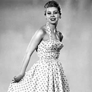 Model from 1950s wearing a dress with a fitted corset style top with a tiny waist