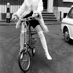 Model Blanche Webb wearing a fur jacket, riding a bicycle. November 1969 Z11350-004