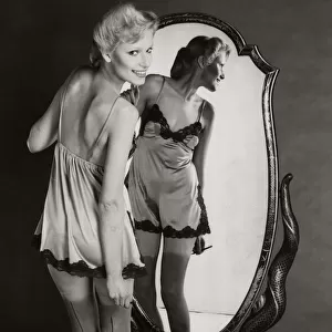 A model dressing up in 1940s style night dress with painted on seamed stockings