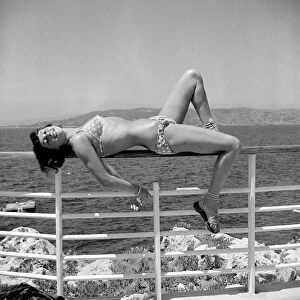 Model posing wearing a bikini lying on railing circa 1949
