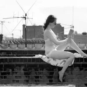 A model wearing a bikini reading a book as she sunbathes on a rooftop on Kings Road in A model wearing a bikini reading a book as she sunbathes on a rooftop on Kings Road in