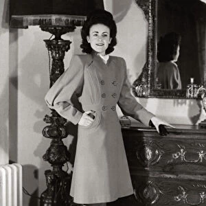 A model wearing a harella coat with new shaped sleeves and flared skirt standing beside a