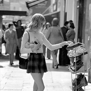A model wearing a polo neck long sleeved top with tartan skirt shopping for shoes