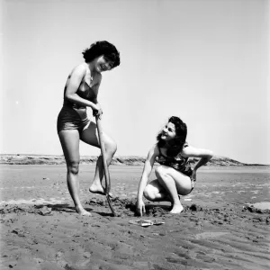 Models wearing the latest beachwear fashions digging. October 1952 C5081-001