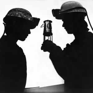 A modern day miner looking at and old miners lamp A modern day miner looking at and old miners lamp