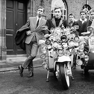 Mods wearing suits and parkas on Motor Scooters covered with extra lights
