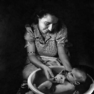 Mother Janet Trayler washing her 4 weeks old baby. August 1943 P009458