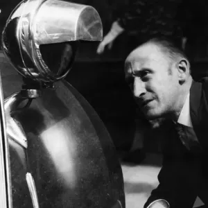 Motorist seen here inspecting a newly installed blackout hood on the headlights of his Motorist seen here inspecting a newly installed blackout hood on the headlights of his
