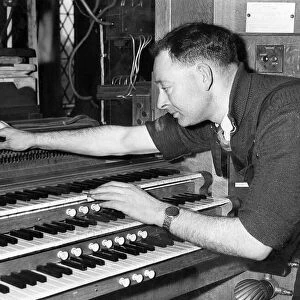 Mr. H. E. Prested test the action of an organ after re-assembly in May 1957