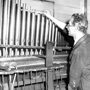 Mr. Leslie Rowland, aged 53, tunes the pipes of this organ on a voicing machine in