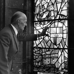 Black and white print of Patrick Feeny examining a stained glass window