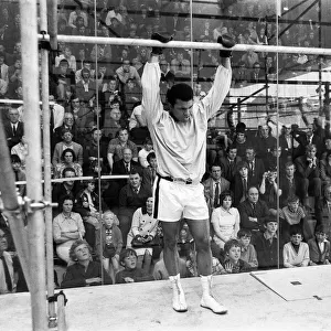 Muhammad Ali in a cage protected by glass from hundreds of fans who paid 50p to watch him