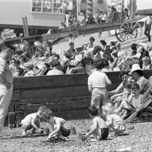 Mum enjoys a sandwich and dad looks on as children build sand castles on the beach Mum enjoys a sandwich and dad looks on as children build sand castles on the beach