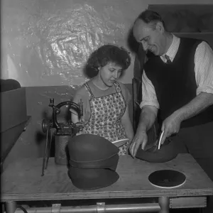 A new employee being shown how to insert a inner liner into a flat cap at the Denham A new employee being shown how to insert a inner liner into a flat cap at the Denham