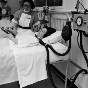 Print of a nurse writing notes on a patient in an intensive care unit Print of a nurse writing notes on a patient in an intensive care unit