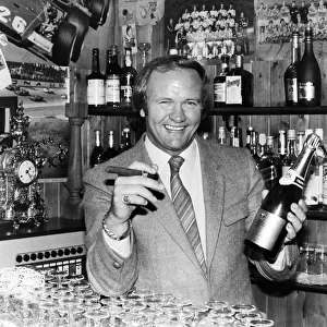 New Manchester United football manager Ron Atkinson holds up a bottle of champagne in one