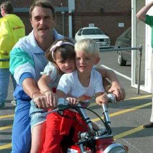 Nigel Mansell with children on a bike at the British Grand Prix Nigel Mansell with children on a bike at the British Grand Prix