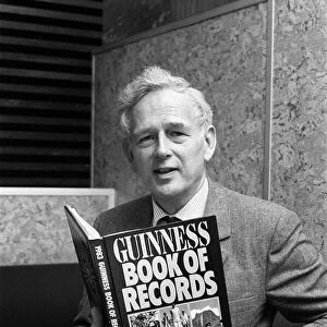 Norris McWhirter holding a copy of the Guinness Book of records