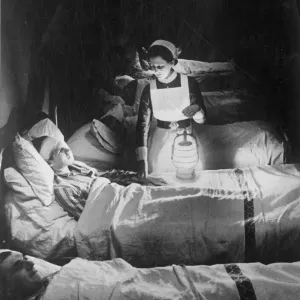 A nurse holiding a lamp as she visits patients on a ward at Westminster hospital