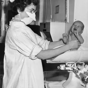 A nurse pictured holding and weighing a baby December 1956 A nurse pictured holding and weighing a baby December 1956